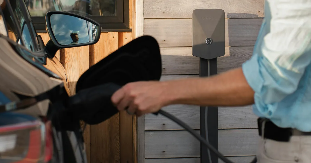 Voiture électrique branchée sur borne murale alimentée par panneaux solaires